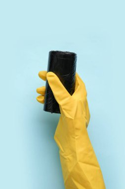 Mavi arka planda çöp torbaları olan kauçuk eldiven verin.