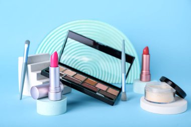 Mavi arka planda dekoratif sıva podyumları ve kozmetik ürünleri