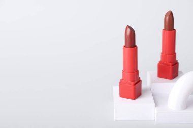 Gri arkaplanda dekoratif alçı podyumlar ve rujlar