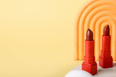 Sarı arka planda dekoratif alçı podyumlar ve rujlar.