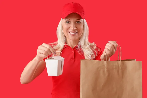 Ältere Kurier Mit Schachtel Mit Lebensmitteln Und Papiertüte Auf Rotem — Stockfoto