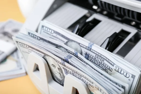 Stock image Modern cash counting machine with dollar banknotes on yellow background, closeup