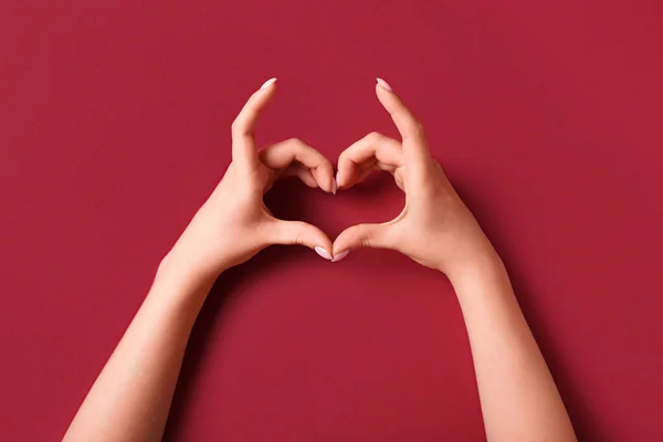 Woman making heart with her hands on red background