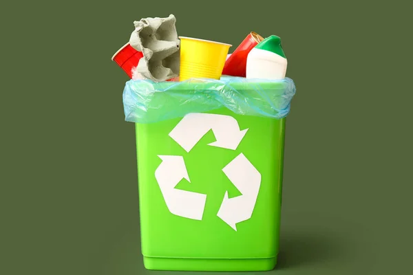 Trash bin with different garbage on green background