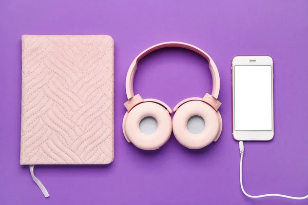 紫色の背景に携帯電話やノートブック付きのヘッドフォン — ストック写真