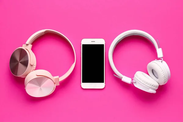 ピンクの背景に携帯電話とヘッドフォン — ストック写真