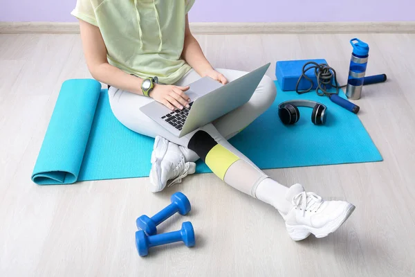 Sporty woman using laptop on mat in gym