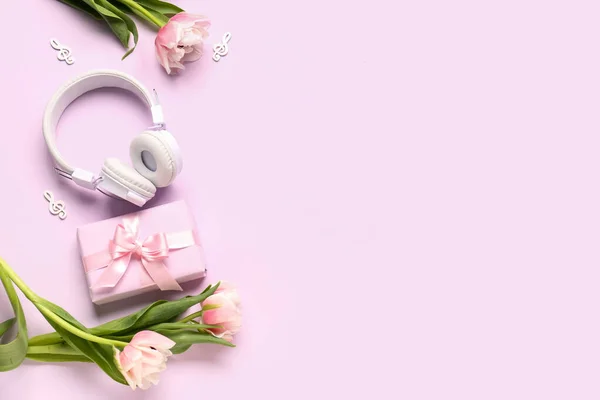 Composition with modern headphones, gift box, music notes and beautiful tulip flowers on color background