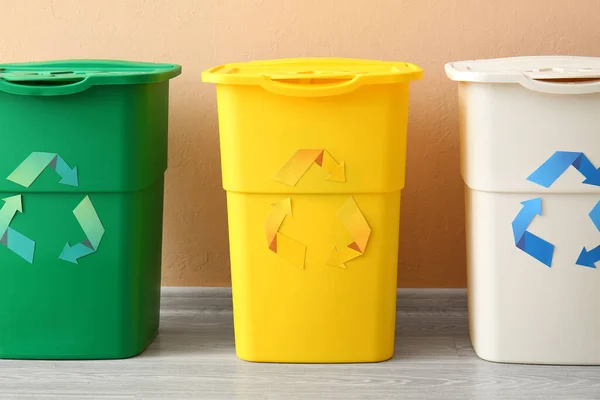 ベージュの壁の近くにリサイクルのシンボルを持つ異なるゴミ箱 — ストック写真