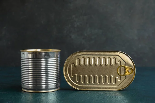 Tin cans with fish on dark table