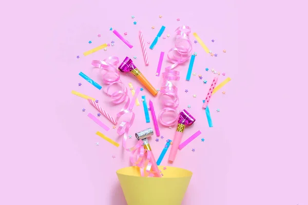 Party cone with confetti and whistles on pink background. Children\'s Day celebration