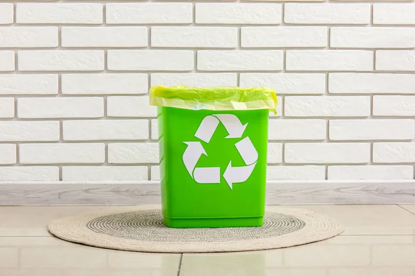 白いレンガの壁の近くのラグのリサイクルのシンボルを持つゴミ箱 — ストック写真