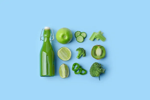 stock image Glass bottle of tasty green juice and ingredients on blue background