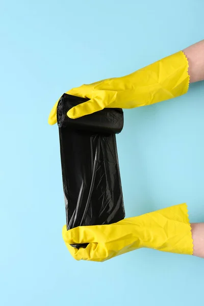 Tangan Sarung Tangan Karet Dengan Kantong Sampah Latar Belakang Biru — Stok Foto