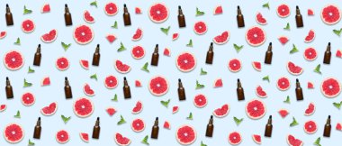 Many bottles of grapefruit essential oil on light background. Pattern for design