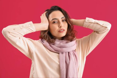 Pembe arka planda eşarplı şık genç bayan, yakın plan.