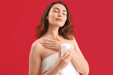 Genç esmer kadın pembe arka planda kozmetik krem kavanozuyla