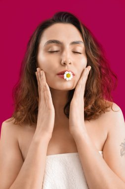 Pembe arka planda papatya çiçeği olan genç esmer kadın, yakın plan.