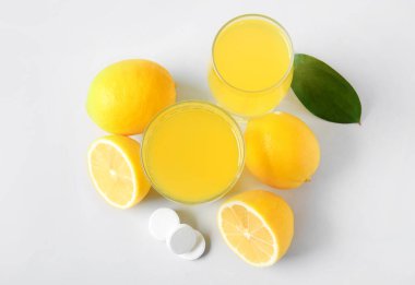 C vitamini tableti suda çözünmüş ve limonlar gri arka planda.