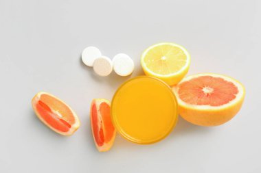 Bir bardak C vitamini tableti suda çözünür ve arka planda meyveler olur.