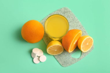 C vitamini tabletli tahta suda çözünür ve turkuaz arka planda meyveler olur.