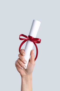 Diploması olan gri arka planda kurdeleli bir kadın.