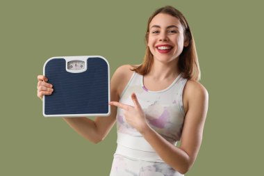 Yeşil arka plandaki pullara işaret eden genç bir kadın.