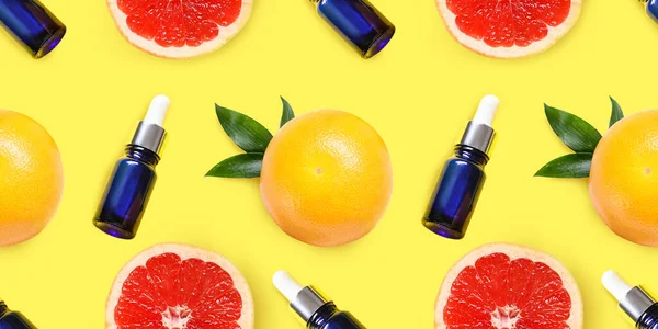 Many grapefruits and bottles of essential oil on yellow background