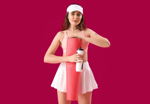 有瓶装水和粉色背景垫子的胖胖的年轻女子 — 图库照片