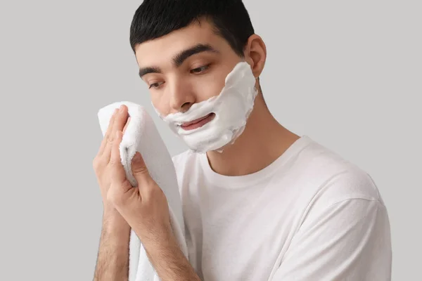 Young Man Wiping Shaving Foam Face Light Background — Stock Photo, Image