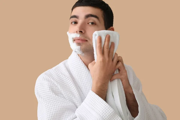 Jovem Limpando Espuma Barbear Rosto Contra Fundo Bege — Fotografia de Stock