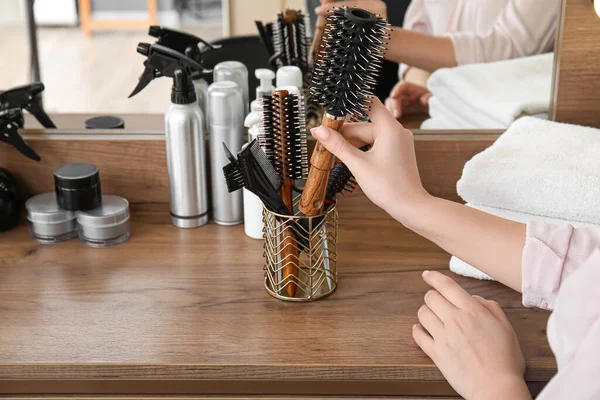 Hairdresser with brushes at table in beauty salon