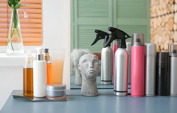 Bottle of spray and hair care products on table in beauty salon