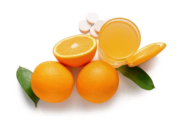 Glass of vitamin C effervescent tablet dissolved in water and oranges isolated on white background