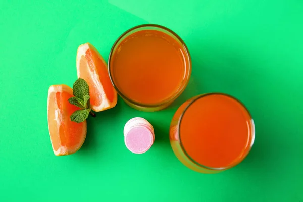 Glasses of vitamin C effervescent tablet dissolved in water and grapefruit pieces on green background