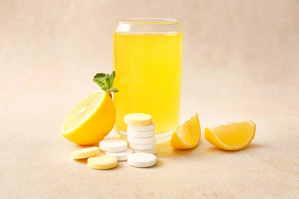 ビタミンC発酵錠剤のガラスは ベージュのグランジテーブルの上に水とレモンに溶解しました — ストック写真