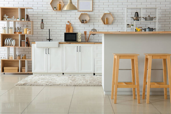 Wooden stools near clean table in interior of modern kitchen