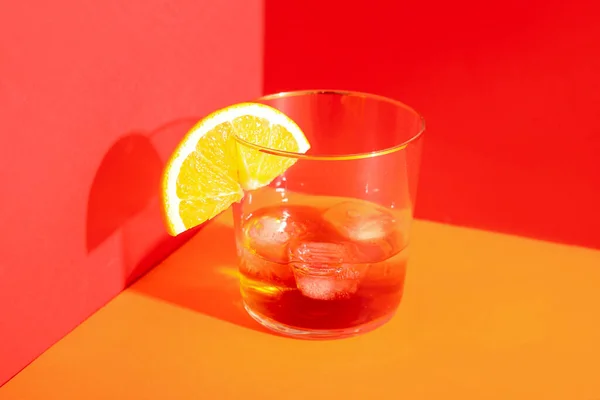 Glas Rum Met Ijsblokjes Sinaasappelschijfje Rode Ondergrond — Stockfoto