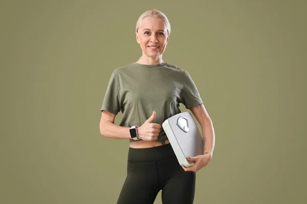 Sporty Mature Woman Scales Showing Thumb Green Background — Stock Photo, Image