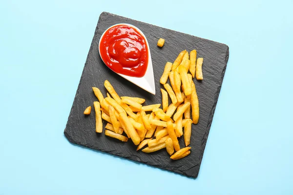 板子上有美味的法式薯条和彩色背景的番茄酱 — 图库照片