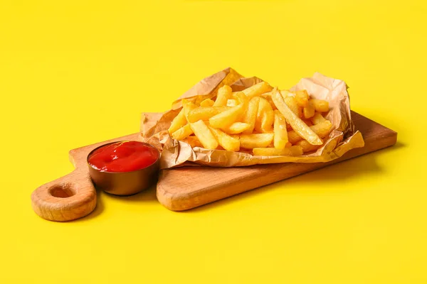 木制木板 配上美味的薯条和黄色背景的番茄酱 — 图库照片