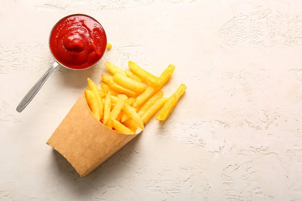 纸盒上有美味的薯条和浅色背景的番茄酱 — 图库照片