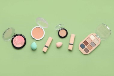 Yeşil arka planda süngerleri olan dekoratif kozmetikler