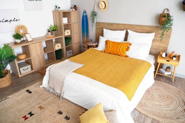 Sörf tahtası, ev bitkileri ve raf ünitesiyle aydınlık yatak odasının içinde.