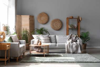 Koltukları, çiçekleri ve masası olan aydınlık oturma odasının içinde.