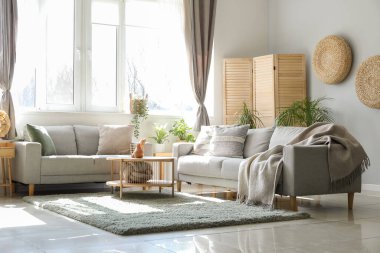 Koltukları, çiçekleri ve masası olan aydınlık oturma odasının içinde.