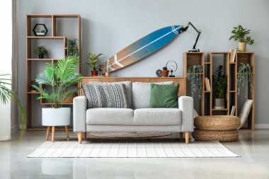 Sörf tahtası, raf ünitesi ve kanepesi olan bir oturma odası.