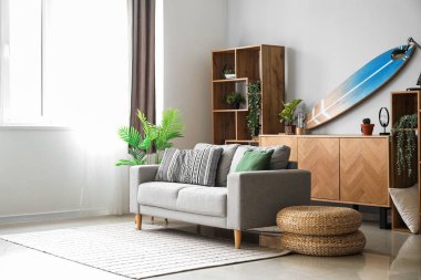 Sörf tahtası, raf ünitesi ve kanepesi olan bir oturma odası.