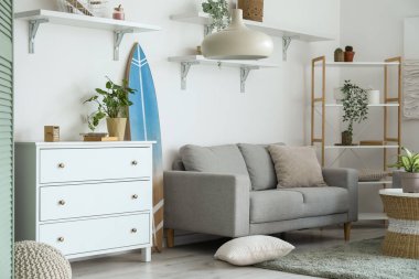 Sörf tahtası, klozeti ve kanepesi olan bir oturma odası.