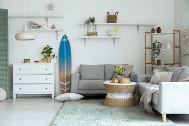 Sörf tahtası, rafları ve kanepeleri olan bir oturma odası.